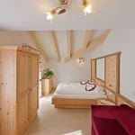 Camera da letto in stile alpino con mobili in legno chiaro e soffitto con travi a vista