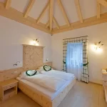 Camera da letto accogliente con letto matrimoniale in legno chiaro e tetto a travi a vista