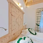 Due letti gemelli in una camera con arredo in legno e cuscini decorati a tema cervi